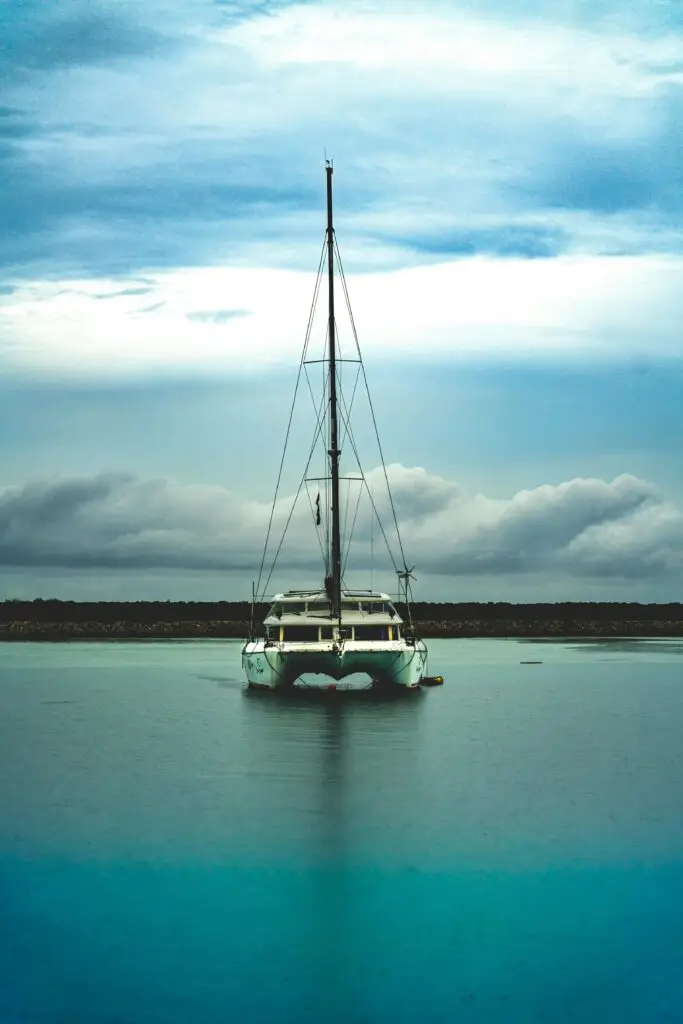 A tranquil scene of a sailboat anchored on a lake under a bright summer sky.